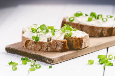Tereyağlı ekmek. Sağlıklı kahvaltı kavramı. Taze soğan, sebzeler. Kopya alanı olan tahta beyaz tablo