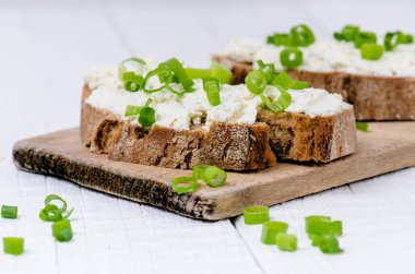 Tereyağlı ekmek. Sağlıklı kahvaltı kavramı. Taze soğan, sebzeler. Kopya alanı olan tahta beyaz tablo