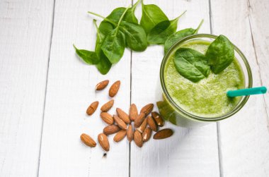 Tahta beyaz arka planda ıspanaklı smoothie. İki yaprak ıspanaklı bir bardak smoothie. Kaçık. Sağlıklı yiyecekler. Kahvaltı..