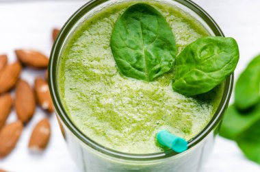 Tahta beyaz arka planda ıspanaklı smoothie. İki yaprak ıspanaklı bir bardak smoothie. Kaçık. Sağlıklı yiyecekler. Kahvaltı..