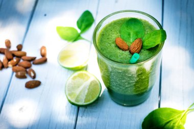 Böğürtlen, ıspanaklı ve portakallı smoothie, ahşap beyaz arka planda. Meyve ve naneli bir bardak smoothie. Böğürtlen, yaprak ve limon, masada ahududu. Meyve, sağlıklı yiyecekler. Kahvaltı..