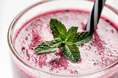 Böğürtlen, ıspanaklı ve portakallı smoothie, ahşap beyaz arka planda. Meyve ve naneli bir bardak smoothie. Böğürtlen, yaprak ve limon, masada ahududu. Meyve, sağlıklı yiyecekler. Kahvaltı..