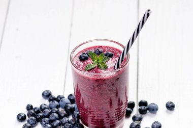 Böğürtlen, ıspanaklı ve portakallı smoothie, ahşap beyaz arka planda. Meyve ve naneli bir bardak smoothie. Böğürtlen, yaprak ve limon, masada ahududu. Meyve, sağlıklı yiyecekler. Kahvaltı..