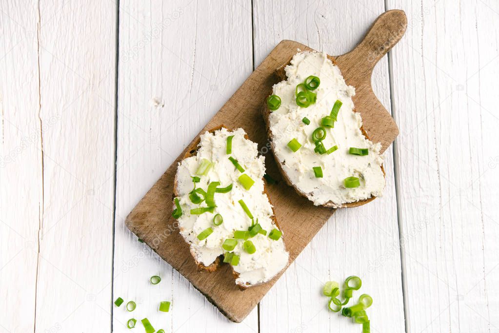 Bread with butter and spread. Concept of healthy breakfast. Spring onion, Vegetables. Wooden white table with copy space