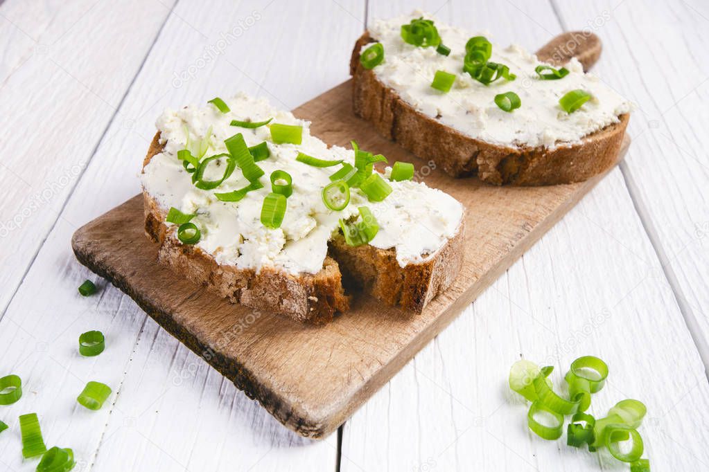 Bread with butter and spread. Concept of healthy breakfast. Spring onion, Vegetables. Wooden white table with copy space