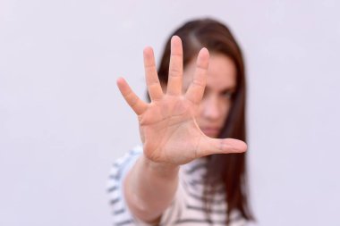 Head and shoulders portrait of young woman with hand in front of face, focus on hand clipart