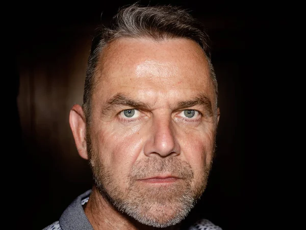 Karanlık bir arka plan üzerinde orta yaşlı adam anız sakal ve yüz portre yakından kısa temiz saç çekici ciddi mavi gözlü sevgilisi