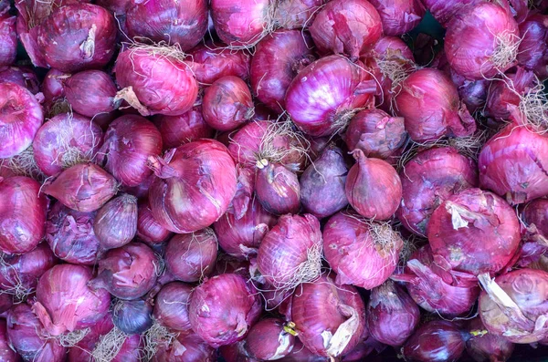 Background food texture of fresh raw red onions on display for sale in a store or farmers market in a healthy diet concept