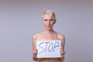 Stop yazı beyaz sayfaya tutan orta yaşlı kadın