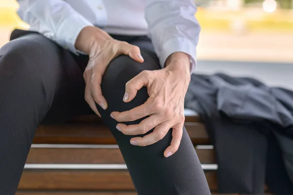 Zakenvrouw Houdt Haar Pijnlijke Knie Zittend Een Bankje — Stockfoto