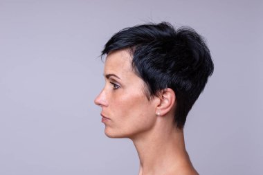 Yan görünümü tarafsız arka plan üzerinde kısa koyu saçlı bir kadın portresi