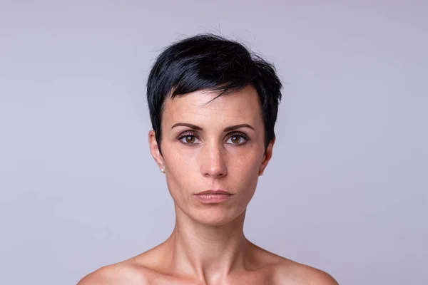 Frontal portrait of a woman in short darker hair over neutral background