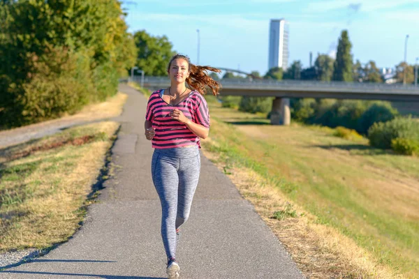 Framifrån Unga Leende Kvinna Som Bär Sportkläder Kör Längs Floden — Stockfoto