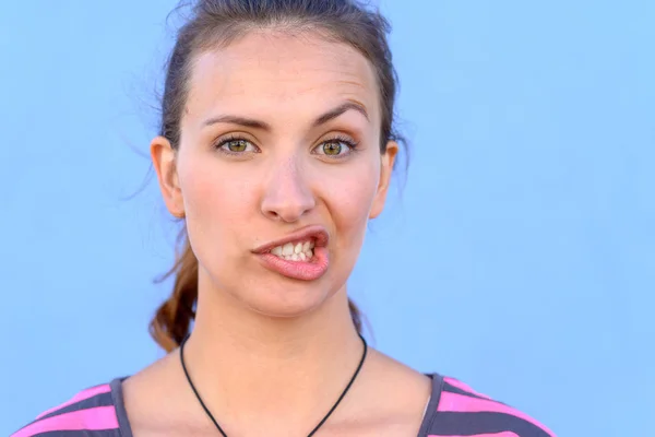 Attraktive Junge Frau Zieht Einen Lustigen Gesichtsausdruck Über Einen Blauen — Stockfoto