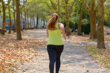 O onun günlük egzersiz ve egzersiz sağlık ve fitness kavram sahiptir gibi bir parkı ile çalışan tombul orta yaşlı bir kadın arkadan görünüm