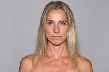 Çıplak omuz baş ve omuz portre Grey yakından ciddi bir heyecansız ifadesinde kamerayla bakarak çekici Olgun sarışın kadınla