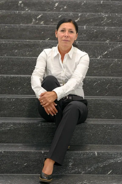 Mature Businesswoman Ponytail White Long Sleeved Shirt Black Pants Sitting — Stock Photo, Image