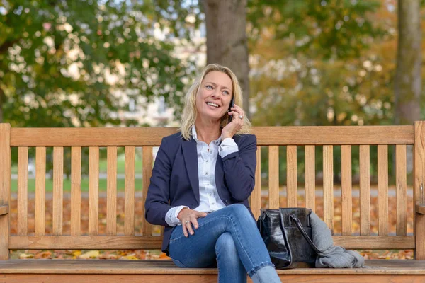 Atractiva Mujer Rubia Mediana Edad Sentada Banco Madera Frondoso Parque — Foto de Stock