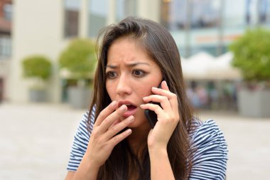Elini onun dudaklarına bir kentsel Caddesi üzerinde açık havada doğal bir jest olarak yükselterek bir cep telefonu konuşurken dehşete genç kadın