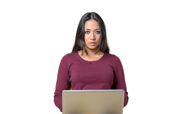 身穿红衬衫的黑发女人坐在笔记本电脑前 用没有感情的脸看着相机 在白色背景查出的半长正面纵向 — 图库照片