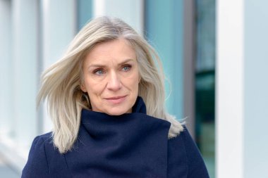 Bir sıcak kış palto ayakta açık havada kameraya gülümseyen mutlu sıcak bir gülümseme ile çekici sarışın kadın giyinmiş