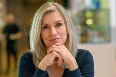 Ellerinin üzerinde dinlenme çenesi ile kamera ÜEP düşünceli kararlı orta yaşlı bir kadın