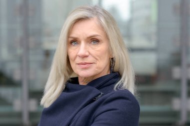 Ciddi düşünceli orta yaşlı profesyonel kadın kamera ile kentsel bir sokak dalgın bir ifadede açık havada bakan