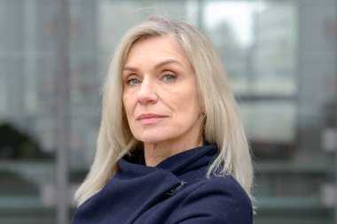 Düşünceli bir kentsel sokak açık havada kamerada bakarak omuz uzunluk sarışın saçlı orta yaşlı kadın