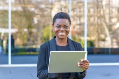 Mutlu genç Afrikalı kadın internet sörf yapabiliyor gibi açık havada yapılan bir kentsel sokak gülümseyerek el tablet kullanma