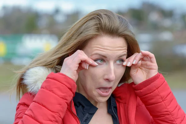 Genç kadın soğuk rüzgarlı bir günde gözlerini ovuşturarak