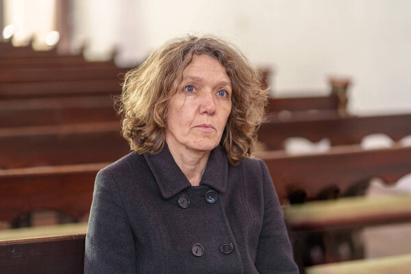 Религиозная женщина, сидящая одна на церковной скамье
