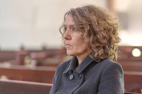 Mujer religiosa sentada sola en un banco de la iglesia — Foto de Stock