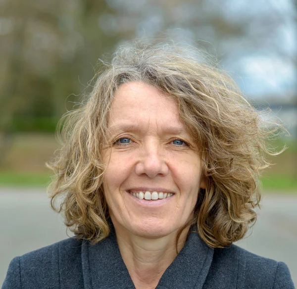 Smiling middle aged woman with curly hair — Stock Photo, Image