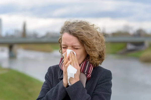 Woman blowing her nose on a tissue outdoors — Stock Photo, Image