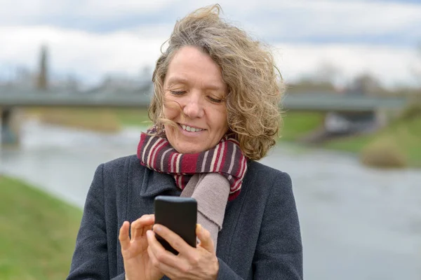 Feliz sonriente mujer mensajes de texto en su teléfono móvil — Foto de Stock