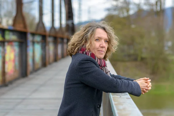 Relaxed happy woman leaning on a bridge parapet — Stock Photo, Image