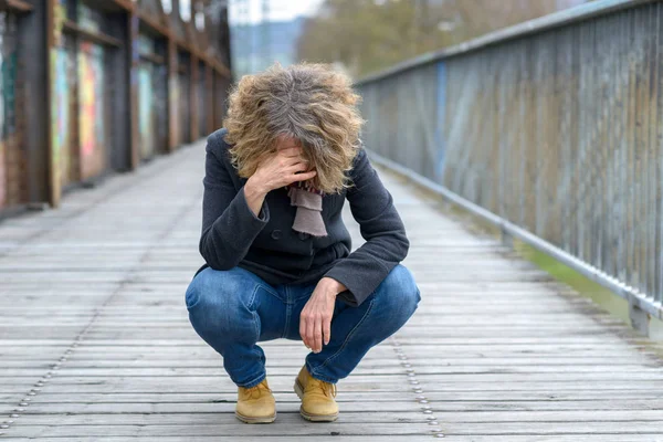 Mujer abatida sentada en un puente — Foto de Stock