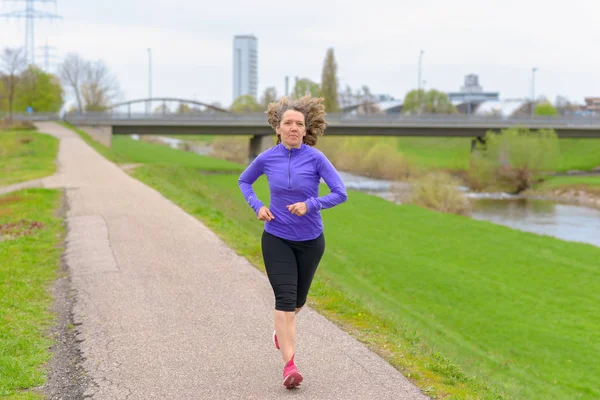 Mujer atlética corriendo junto a un río — Foto de Stock