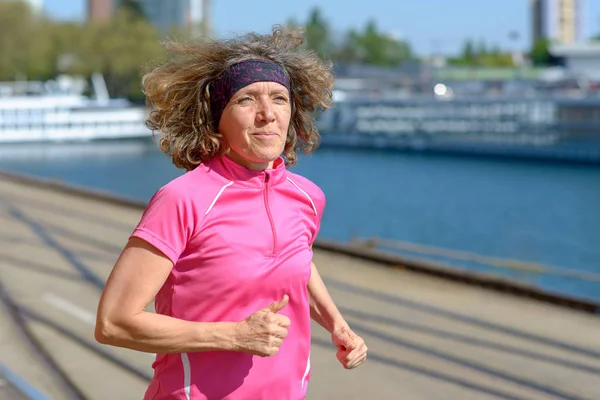 Mujer corriendo junto a un canal urbano o un río — Foto de Stock