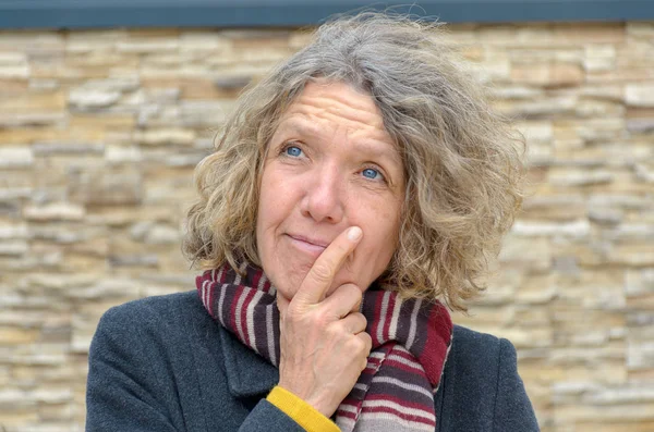 Thoughtful middle-aged woman with hand to chin — Stock Photo, Image