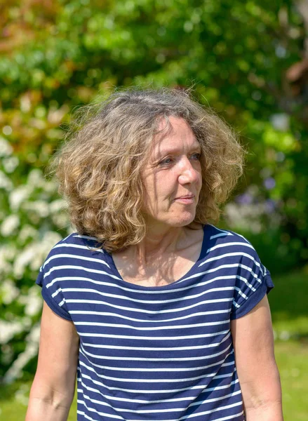 Attractive middle-aged woman walking in a garden — Stock Photo, Image