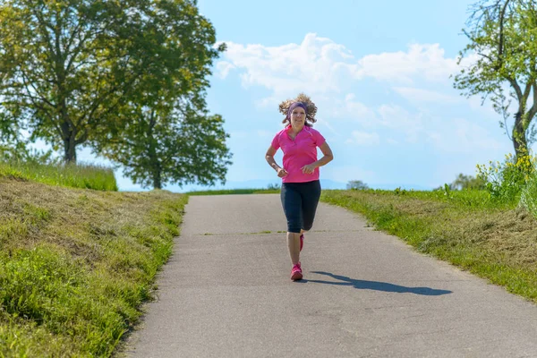 Ajuste mujer de mediana edad corriendo en un camino de campo — Foto de Stock