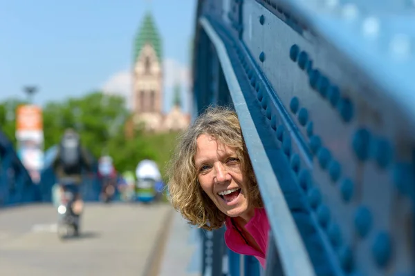 Mujer riendo juguetona mirando a través de un puente — Foto de Stock