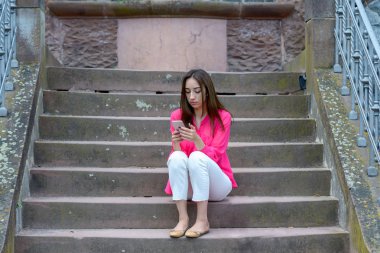 Dış çimento merdivenlerinde oturan genç kadın
