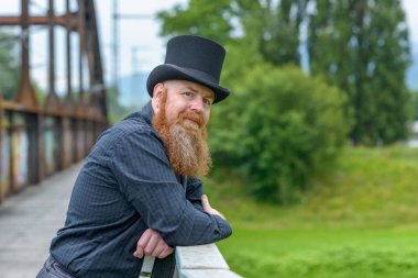 Gülümseyen dost sakallı adam bir köprüye yaslanmış