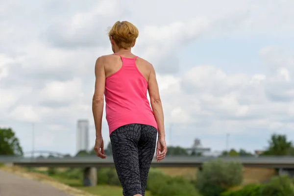 Mujer esbelta y deportiva caminando a lo largo de un sendero — Foto de Stock