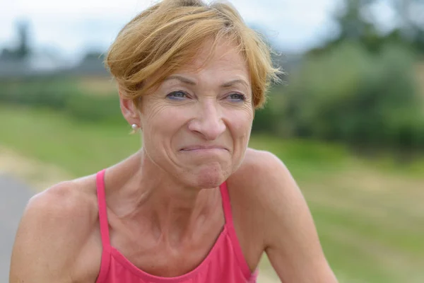 Middle-aged woman grimacing with a wry expression — Stock Photo, Image