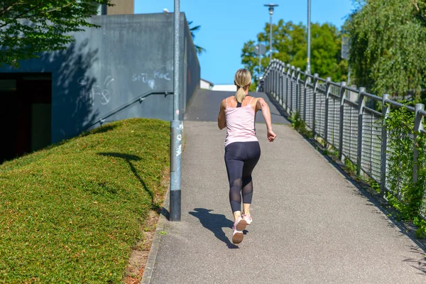 Mujer en forma corriendo por una colina urbana empinada — Foto de Stock