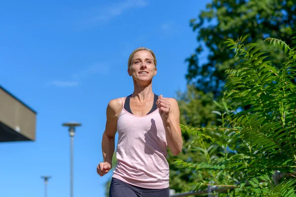 Mujer sonriendo mientras corre al aire libre — Foto de Stock