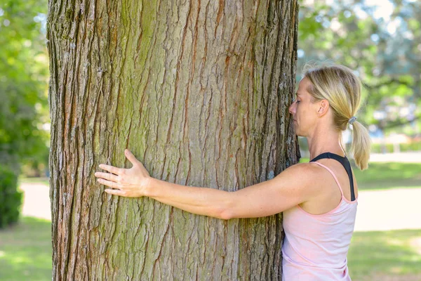 Joven mujer soñando mientras abraza un árbol — Foto de Stock
